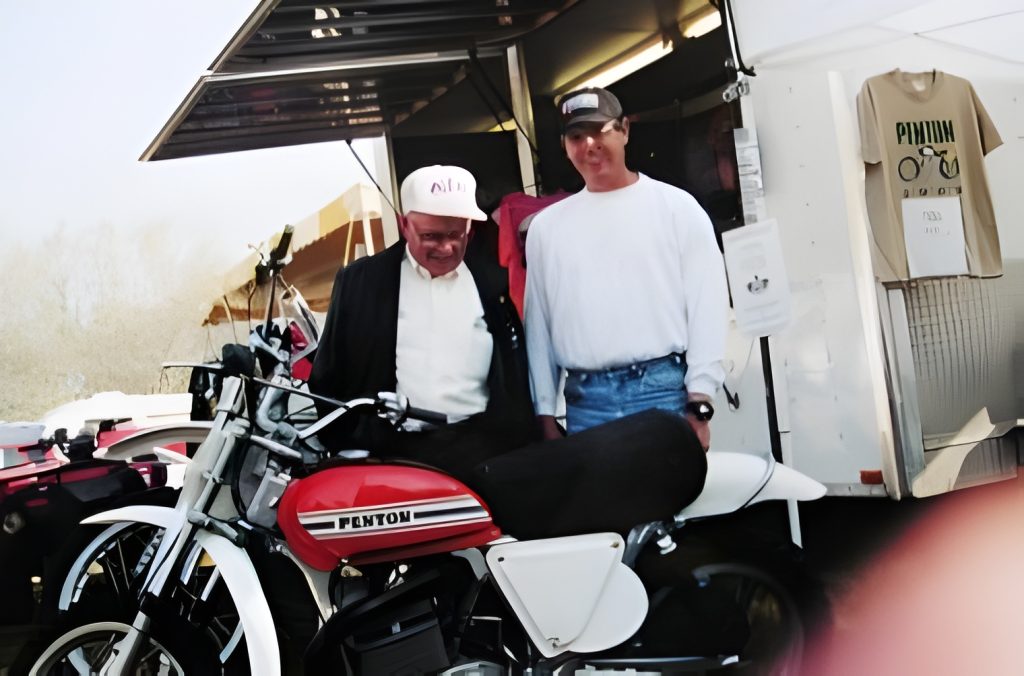 Two men by a vintage red motorcycle.