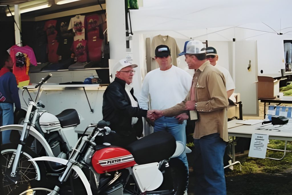 Men handshake near motorcycles at outdoor shop