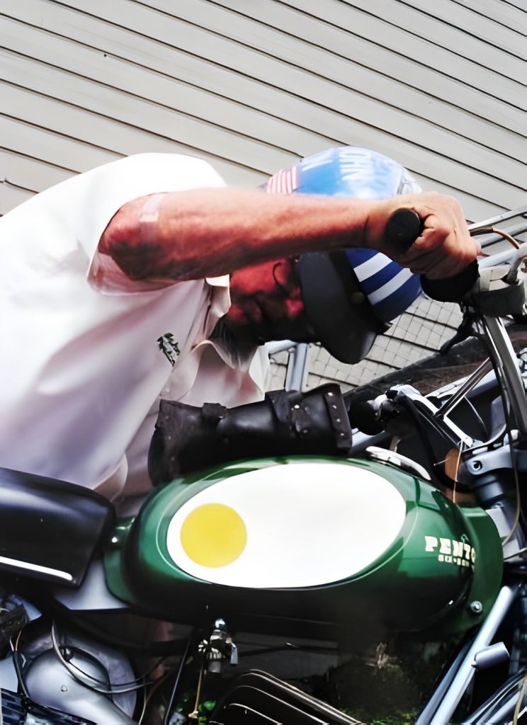 Person maintaining vintage motorcycle outdoors.