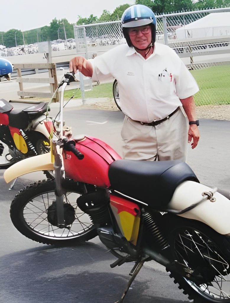 Person standing with vintage motorcycle.