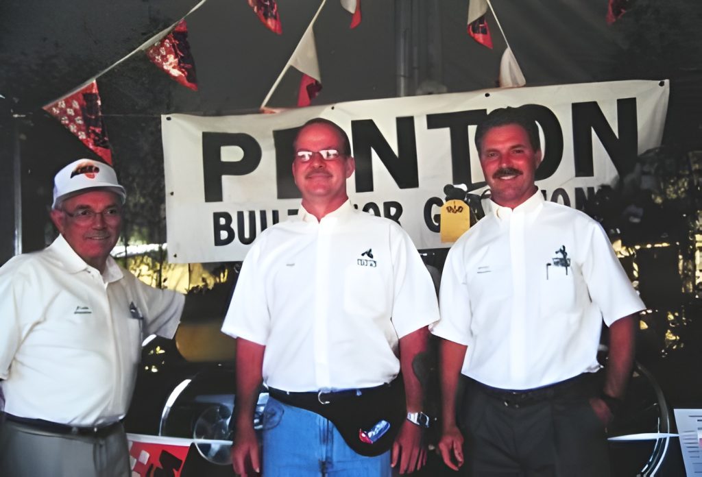 Three men in front of Penton banner.