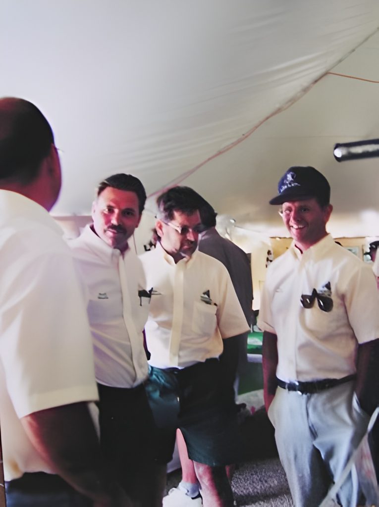Group of men under a tent, smiling.