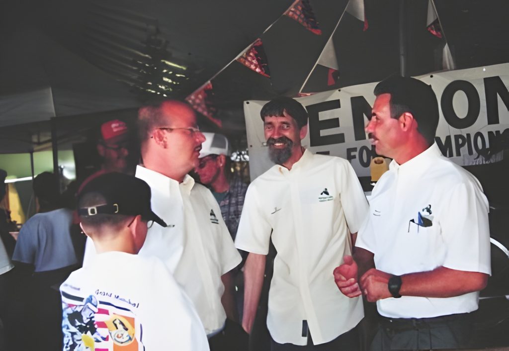 People conversing at an event with banner in background.