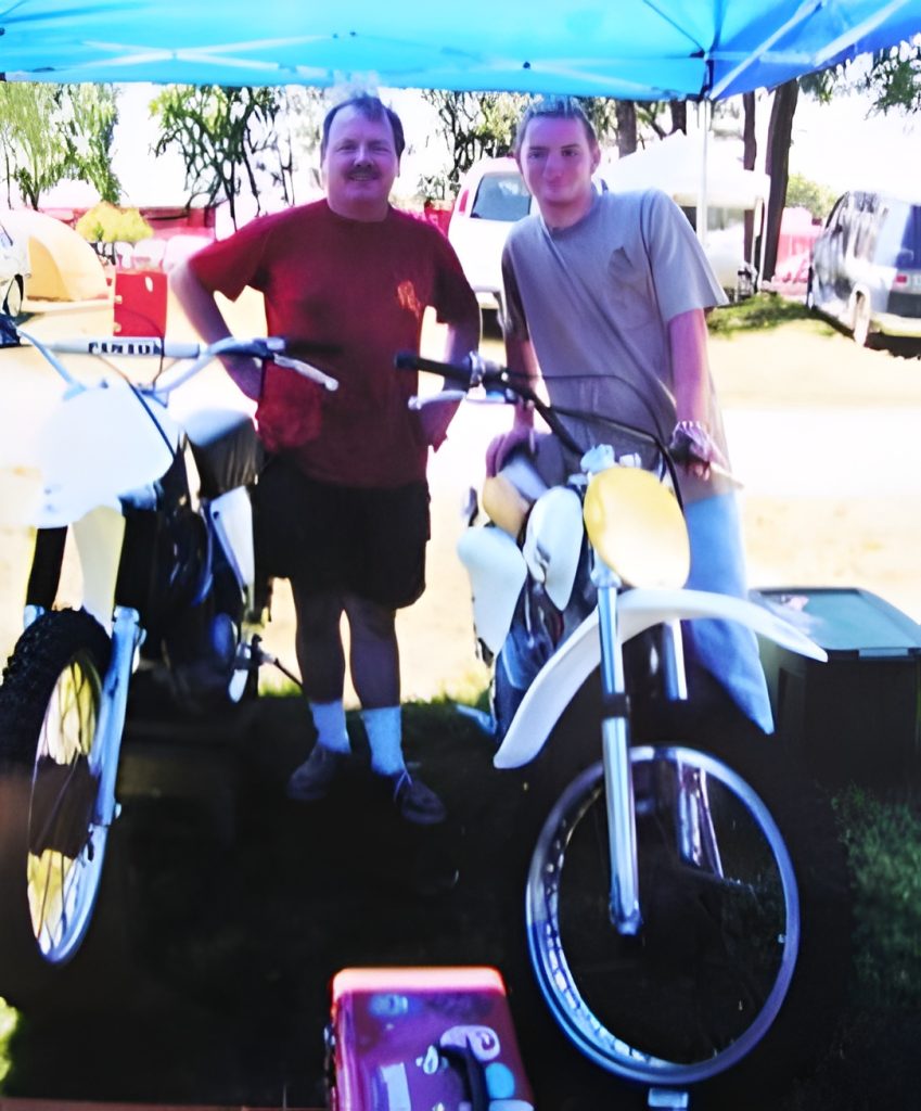 Two people with motorcycles under a tent.