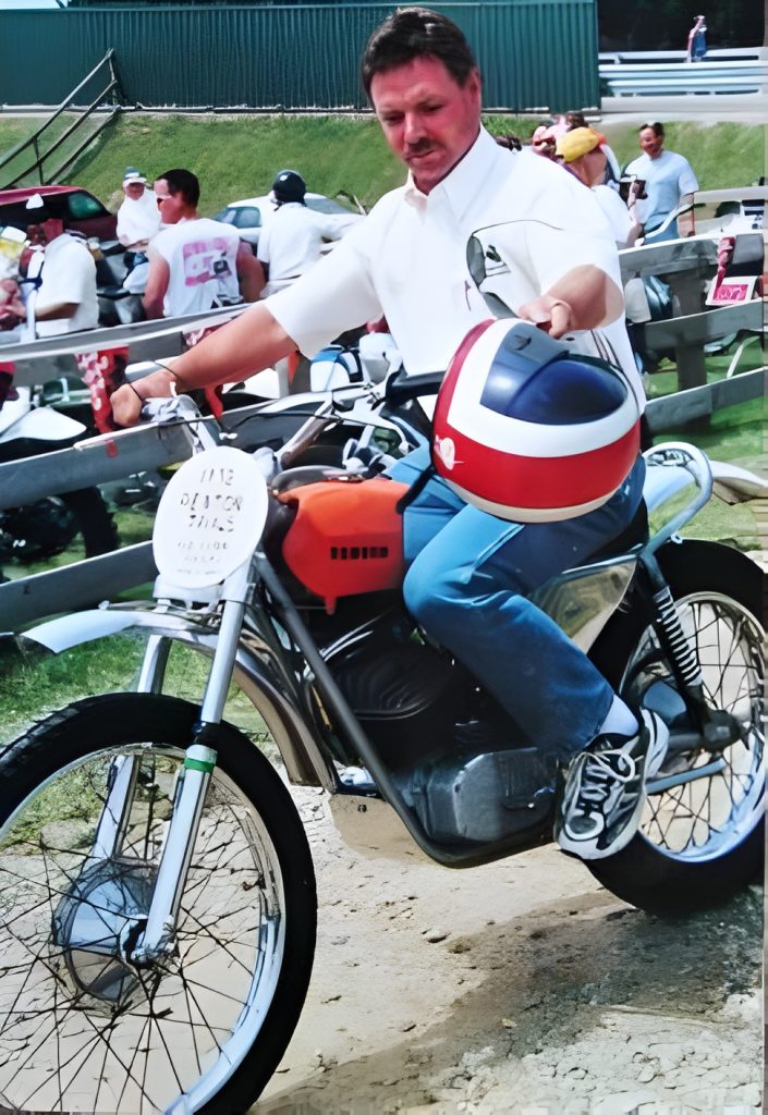 Man on vintage motorcycle in event crowd.