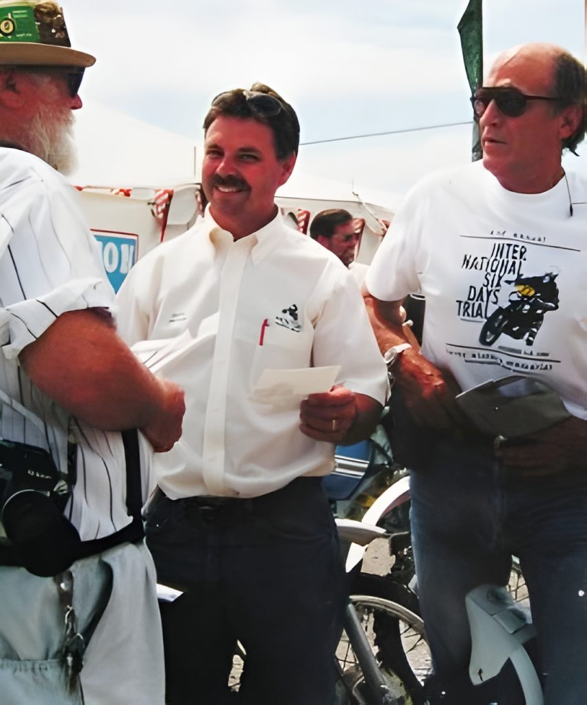 Three men talking outdoors at an event.