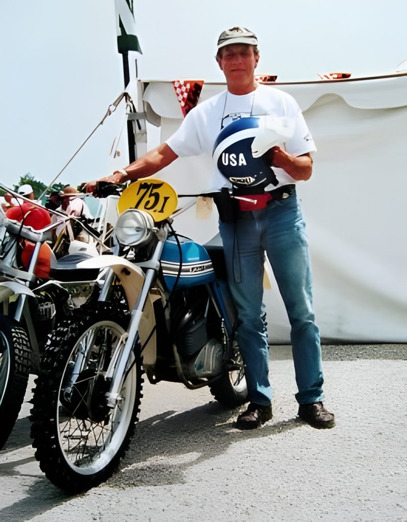 Person holding USA helmet by vintage motorcycle