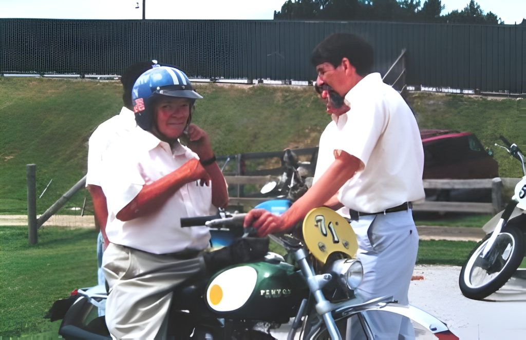 Two men with motorcycles, one adjusting helmet