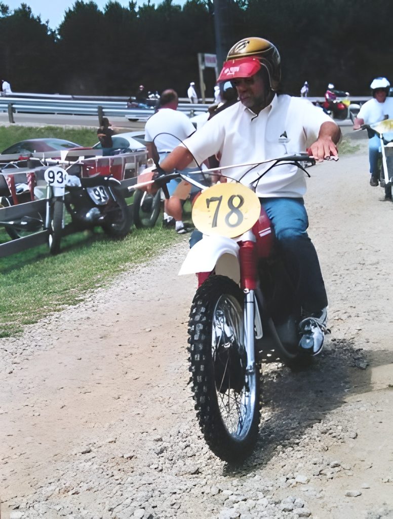 Motorcyclist on dirt path, vintage race setting.