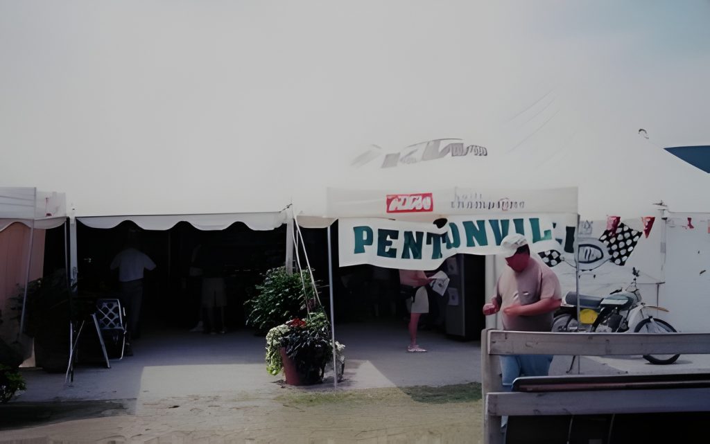 Outdoor tent with Pentonville sign and people nearby.