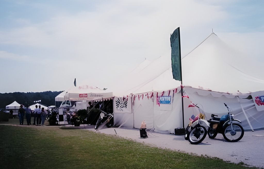 Outdoor event tents with motorcycles and people.