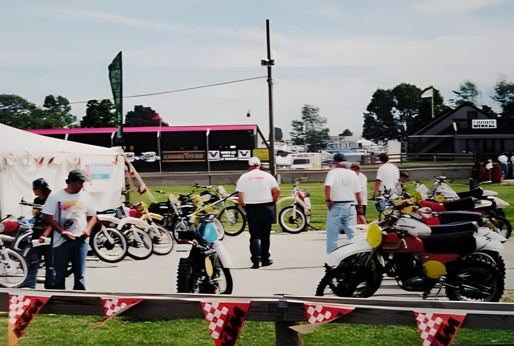 Outdoor motorcycle exhibition with people viewing vintage bikes.