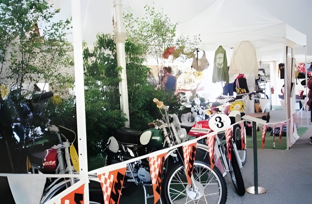 Motorcycles displayed under white tents at outdoor event.