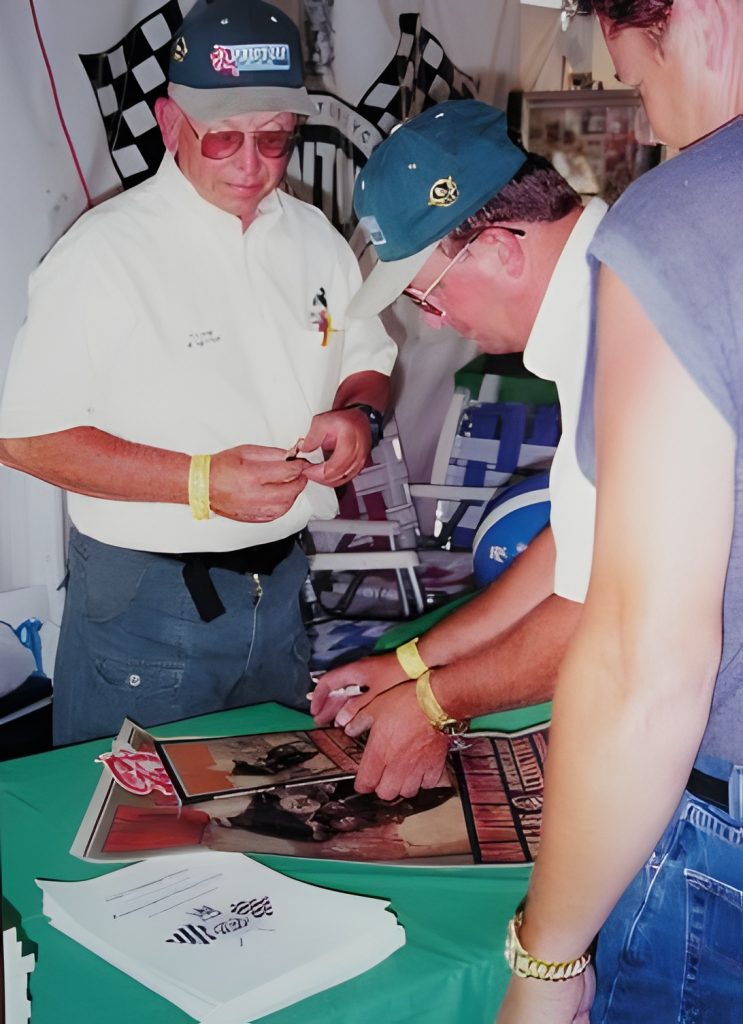 People signing posters at a table event.