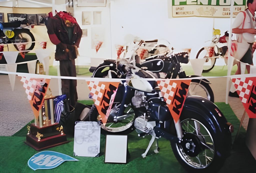Vintage motorcycles on display with trophies and banners