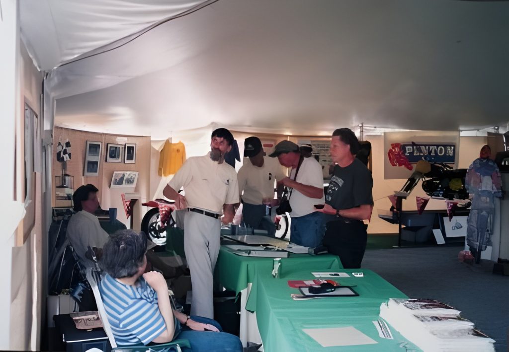 People gathered in a vintage car exhibit tent.