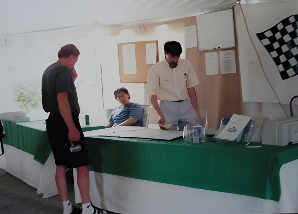 People conversing at a table with a bulletin board.
