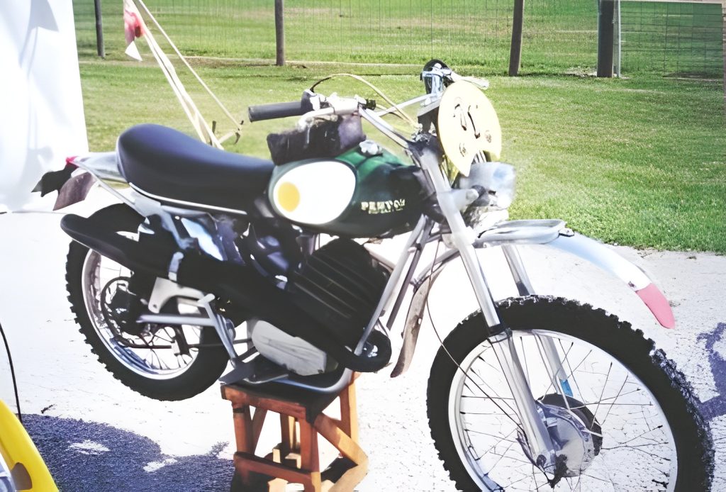 Vintage motorcycle displayed outdoors on a wooden stand.