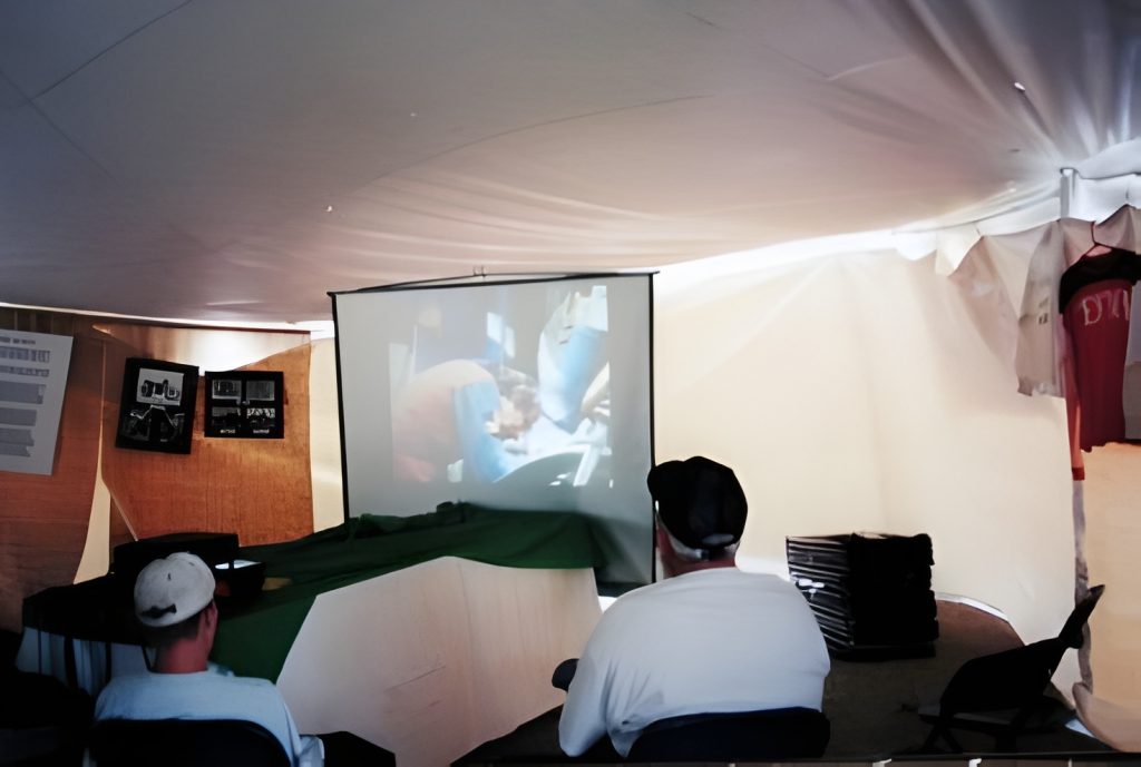 People watching a projected film in a tent.
