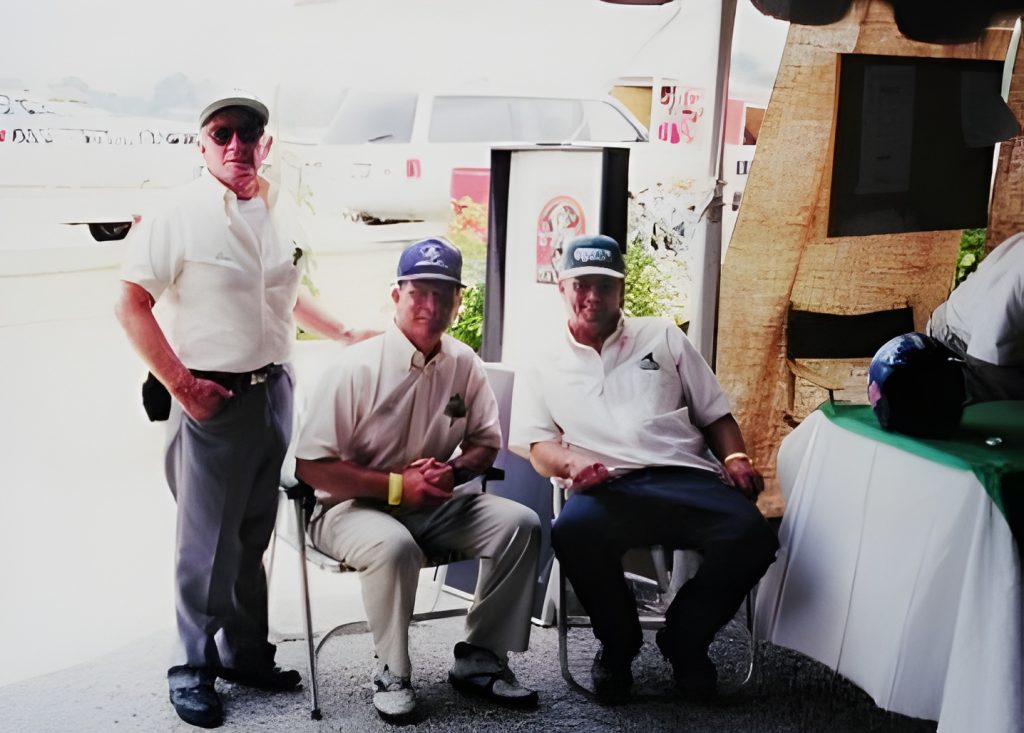 Three men sitting outdoors in casual attire.