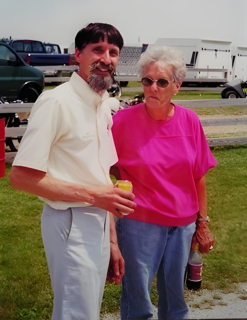 Two people standing outdoors, smiling together.