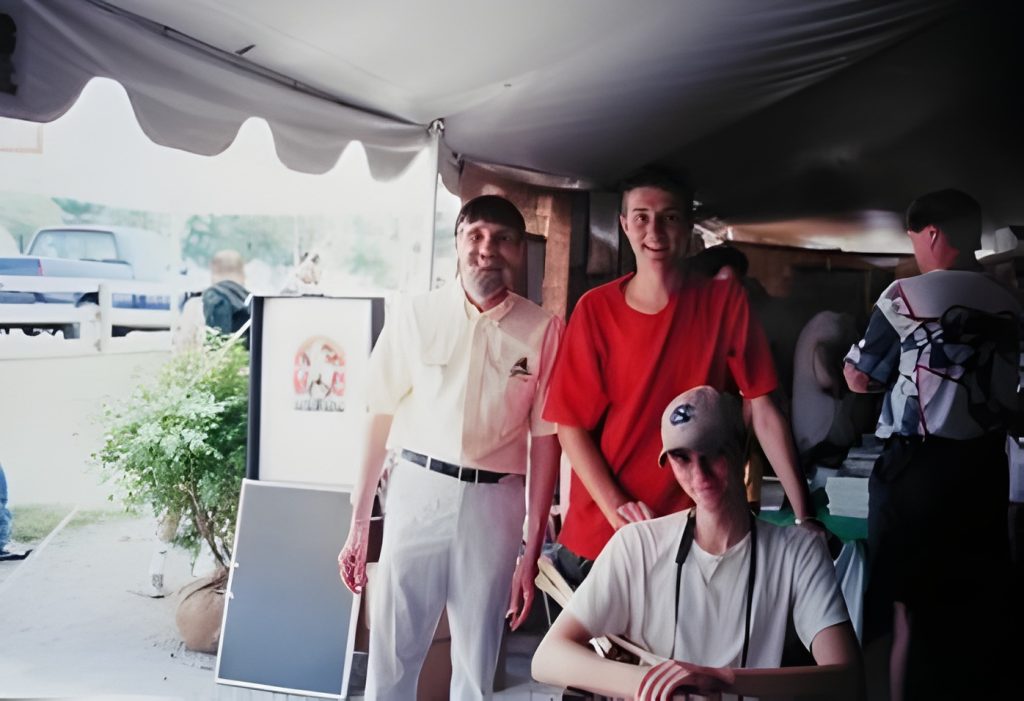 Three people at outdoor event under tent