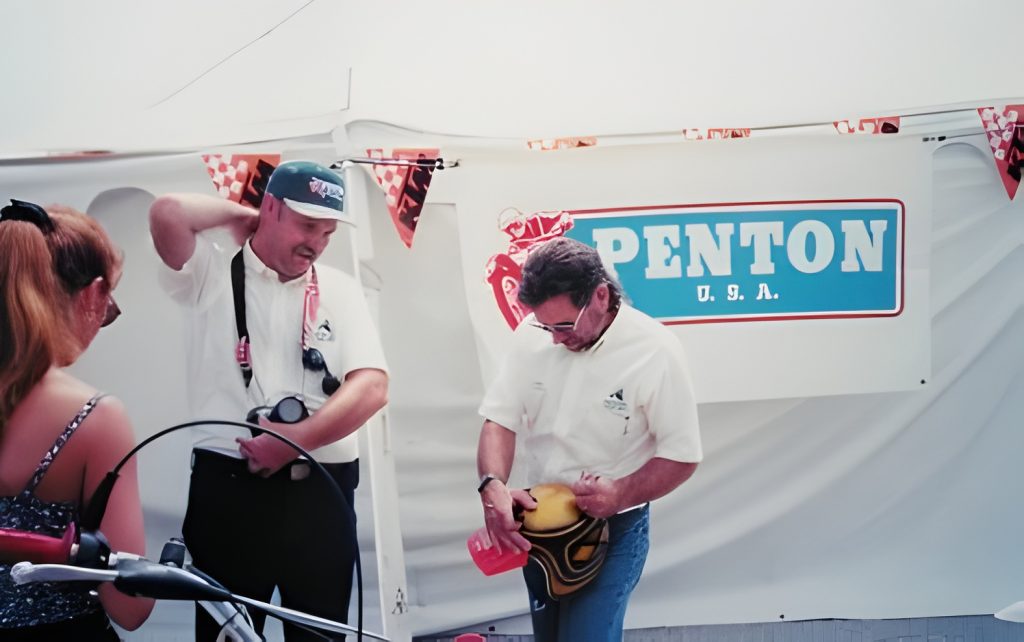 Two men at Penton USA booth, motorcycle event.