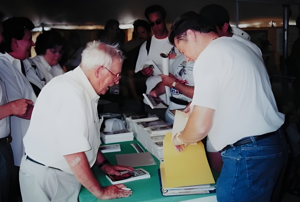 People at book signing event, exchanging books.