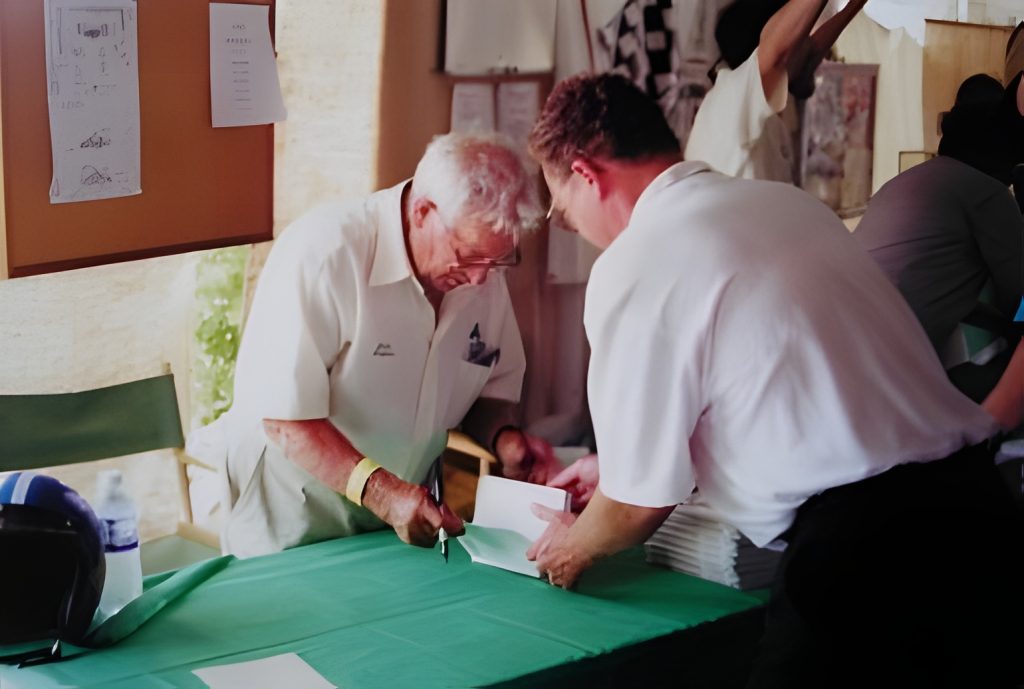 Two people signing papers at a table event.