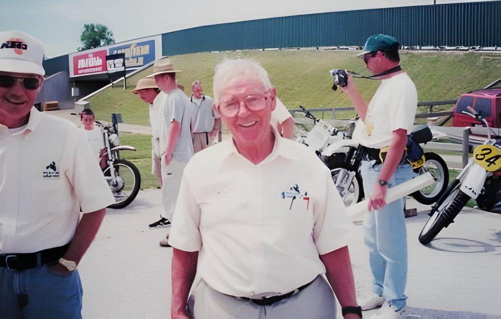 Older man smiling with motorcycles in background.