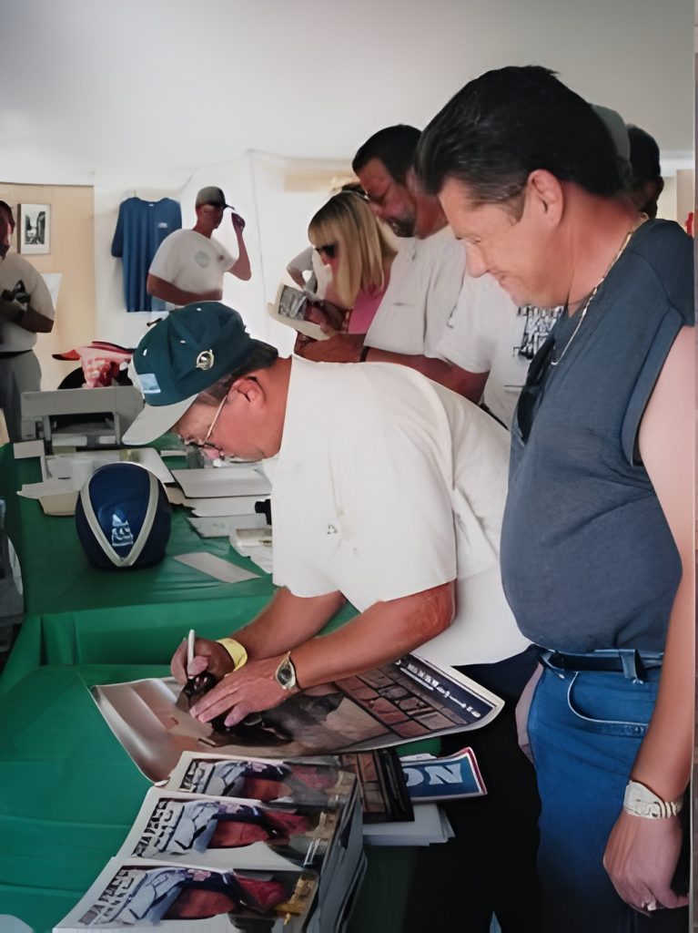 Man signing autographs at event table