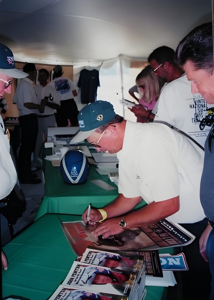 Man signing autographs at booth event.