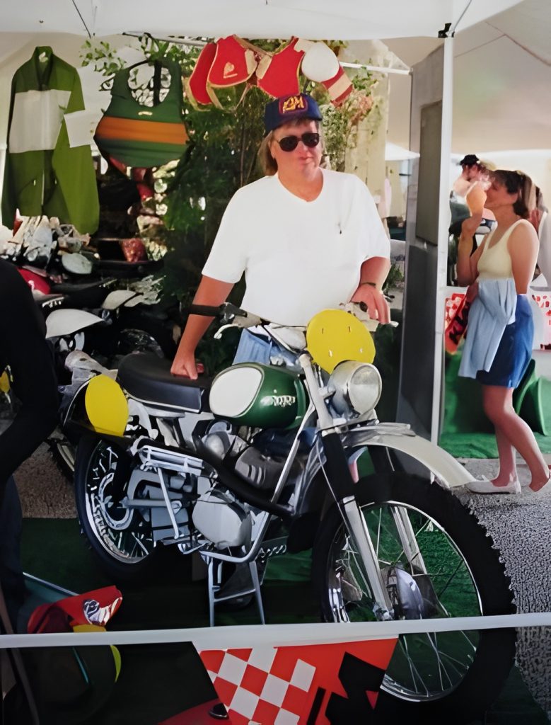 Person with motorcycle at vintage show display.