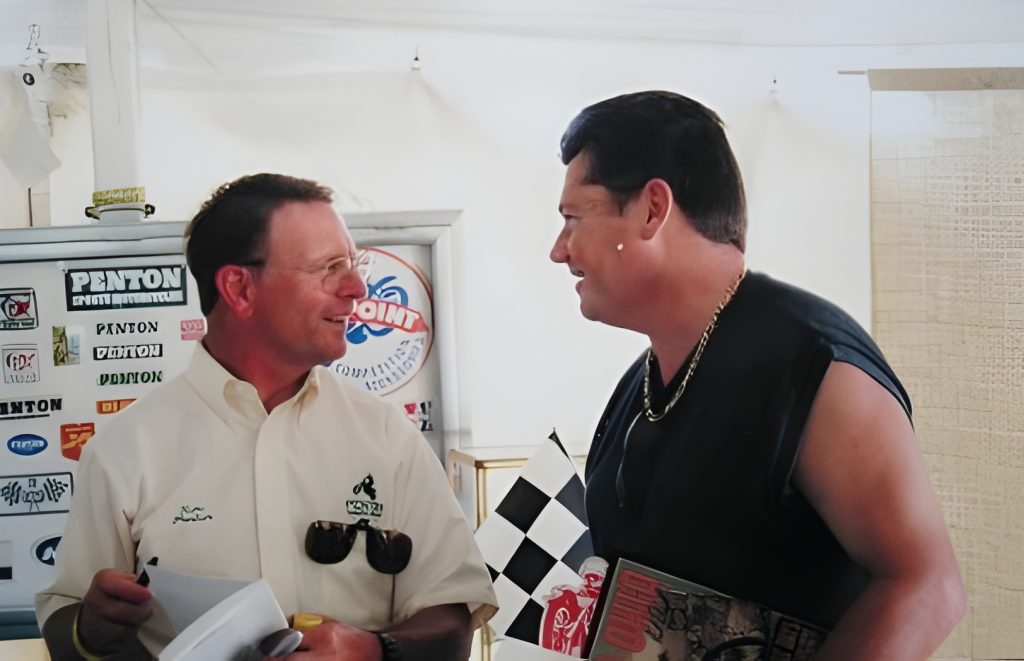 Two men discussing near branded stickers display.