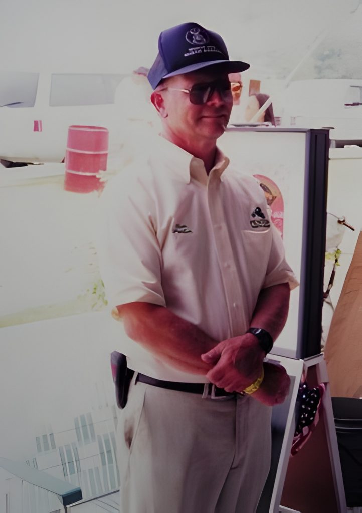 Man in uniform and cap standing outdoors.