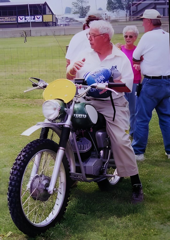 Man with vintage motorcycle in outdoor setting.