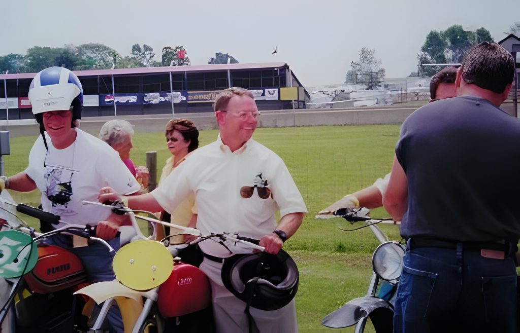 People gathered with motorcycles at a racetrack event.