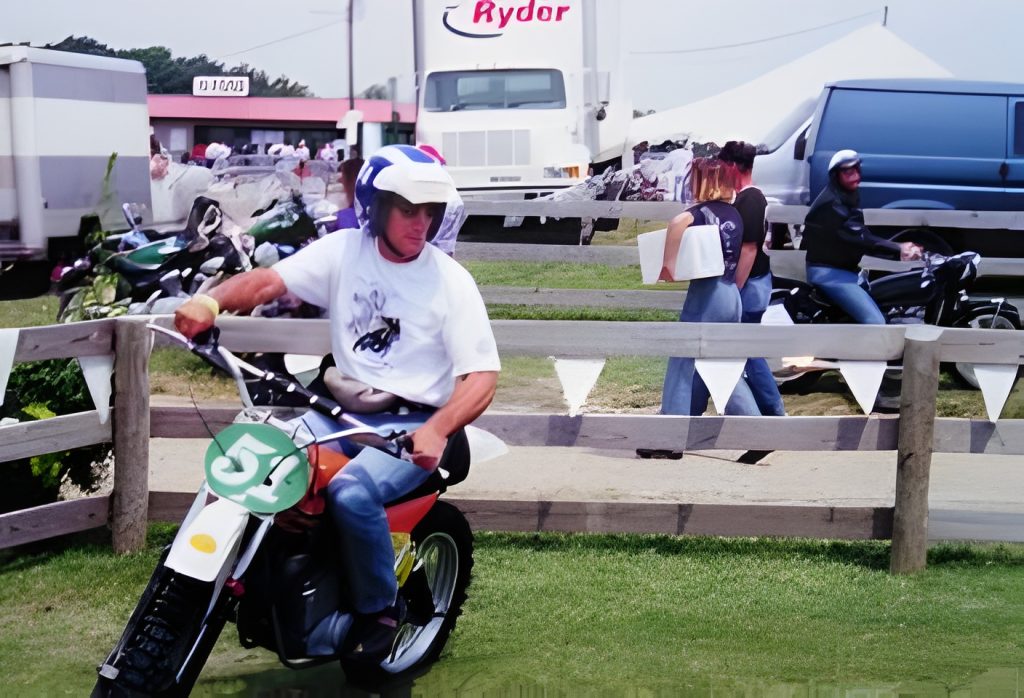 Man riding motorcycle at outdoor event with spectators.