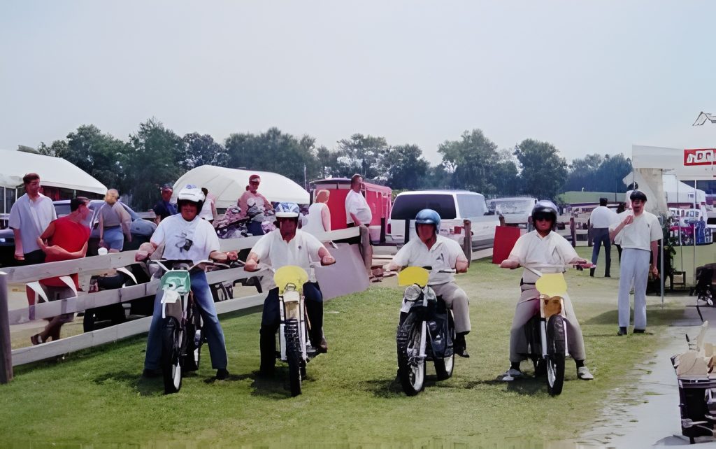Four men on vintage mopeds outdoors.