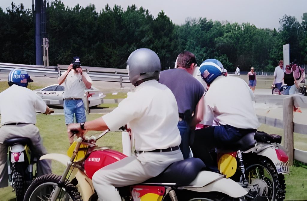People riding motorcycles and filming on roadside