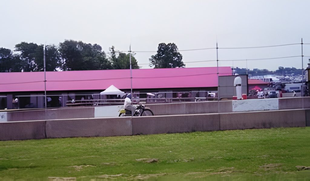 Person on motorcycle near racetrack with red roof