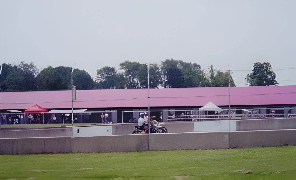 Motorcycles parked near a racetrack with tents.