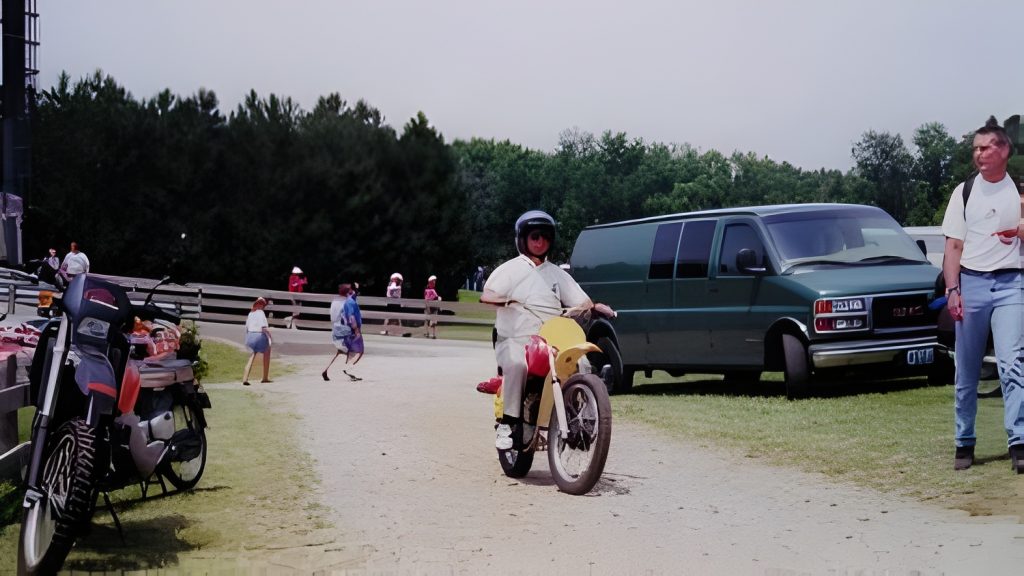 Person riding motorcycle in park near van