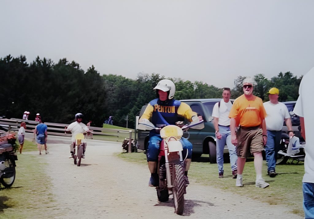 People riding dirt bikes outdoors on a sunny day.