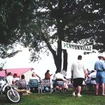 People gather at motorcycle event under Pentonville banner.