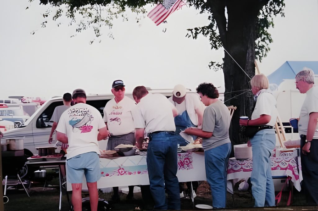 People gathered around a picnic table outdoors.