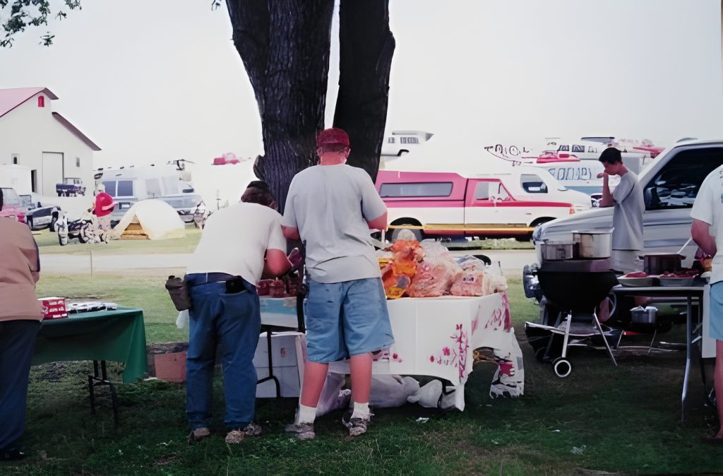 Outdoor barbecue with people and RVs.