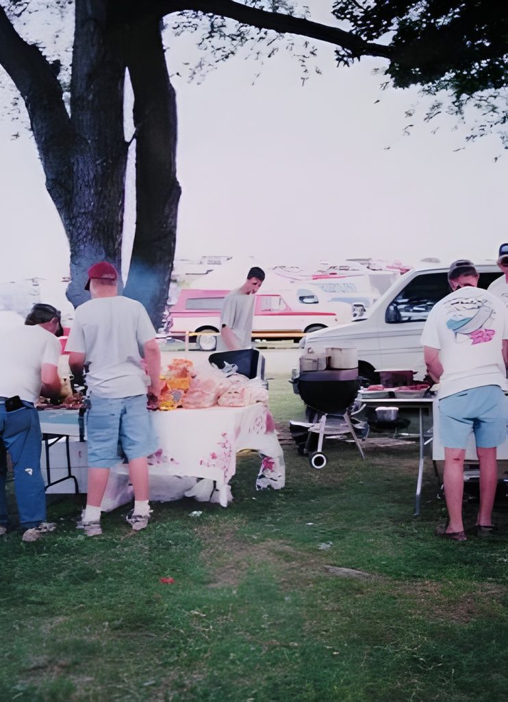 Outdoor picnic with people and grill setup.