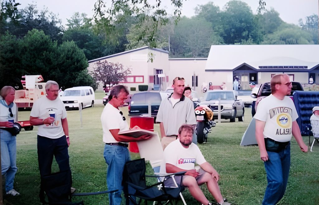 Group of people gathered at outdoor event, smiling.