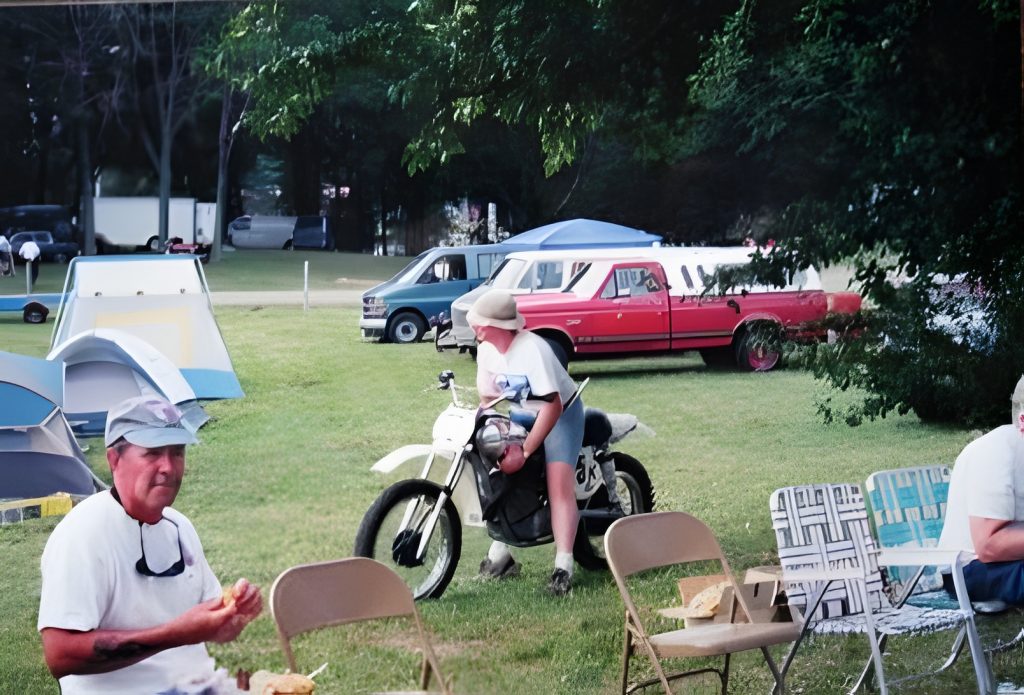 People camping with motorcycles and tents nearby.
